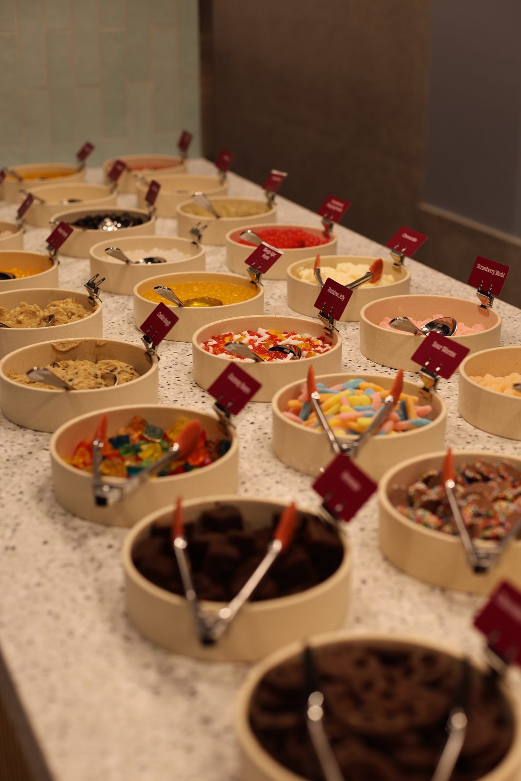 Self-serve topping bar with rows of toppings in a frozen yogurt store