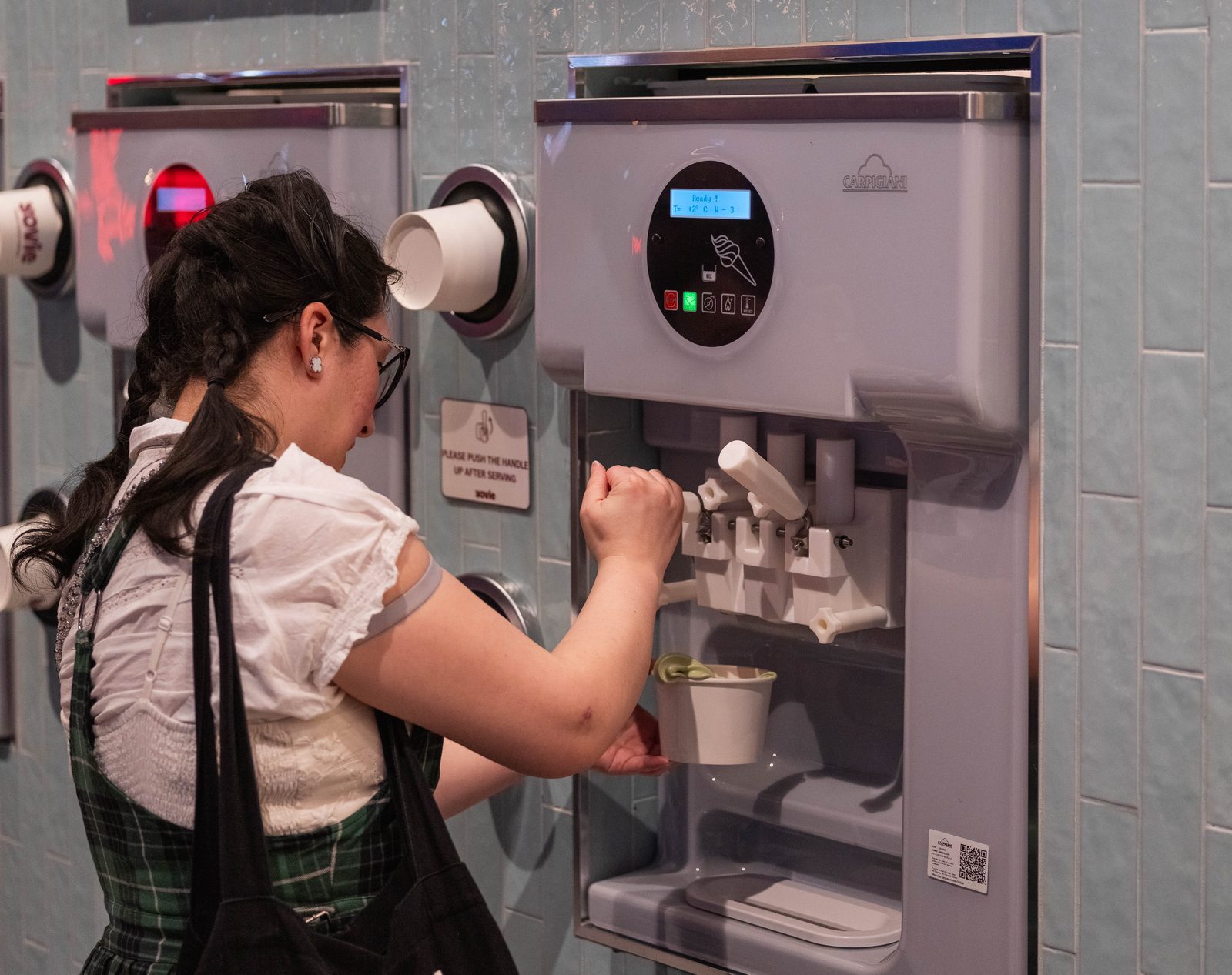 Customer serving matcha frozen yogurt from a self-serve machine