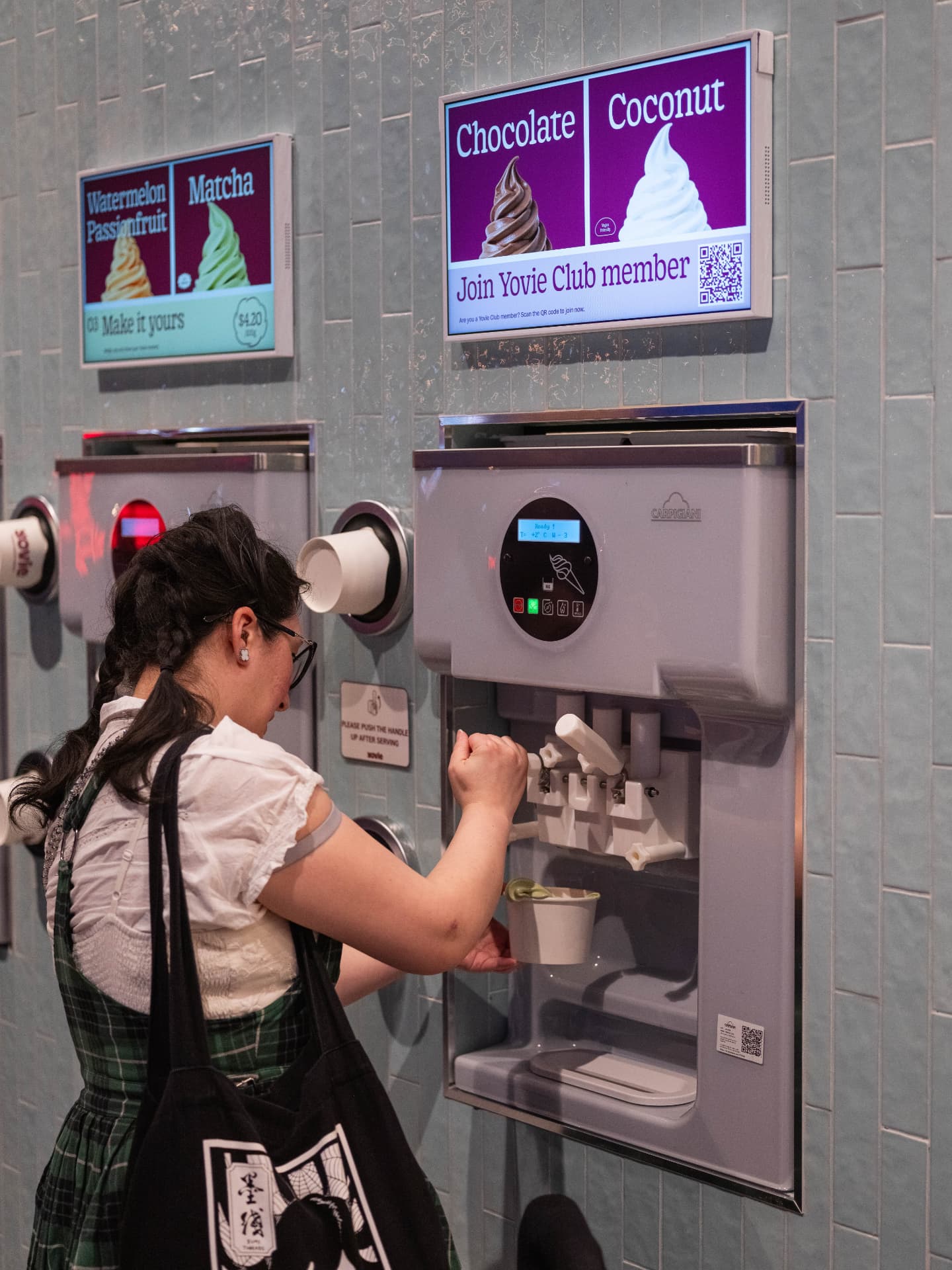 A customer serving frozen yogurt at a YOVIE self-serve machine